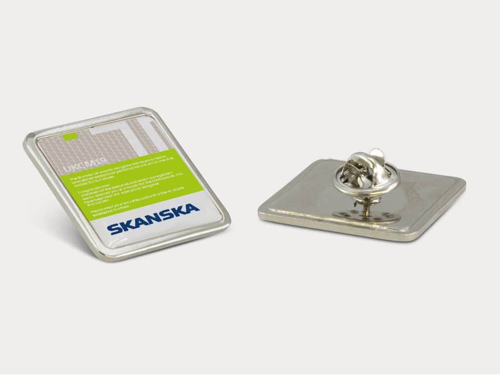 Metal pin badge design mockup for Skanska with branded green and white background.